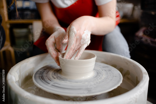 Female hands crafting a pottery cup on a potter's wheel. Handmade and crafting concept. Top horizontal view copyspace.