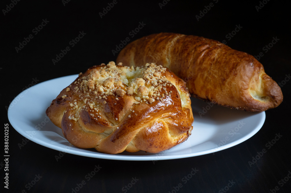 Two sweet bread on white plate with black wooden background