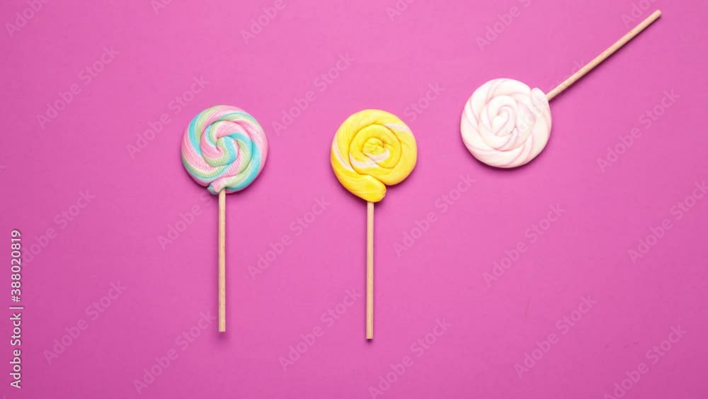 Colorful lollipops appear in turns on a pink background. Stop motion. Colorful lollipops appear in turns on a pink background. Stop motion.