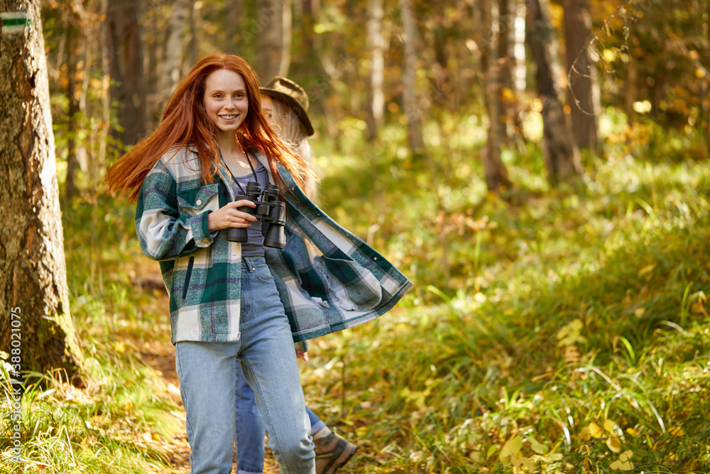 redhead and blonde females have fun during hike in the forest, wearing casual clothes. they laugh, relax redhead and blonde females have fun during hike in the forest, wearing casual clothes. they laugh, relax