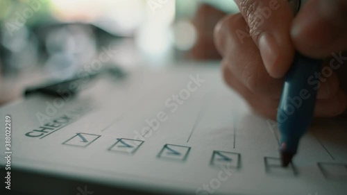 Hand with blue pen marking on checklist box. Close-up