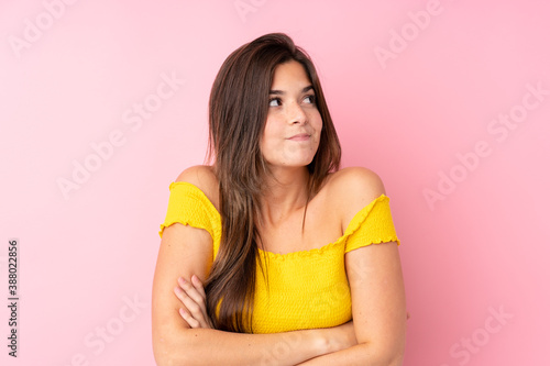 Teenager Brazilian girl over isolated pink background making doubts gesture while lifting the shoulders