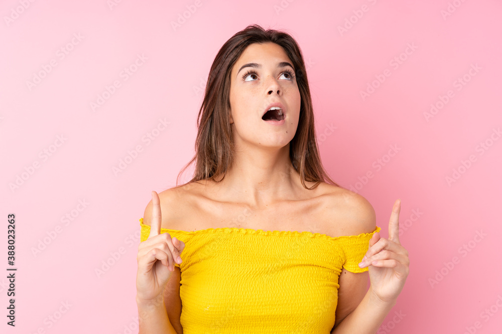 Teenager Brazilian girl over isolated pink background surprised and pointing up Teenager Brazilian girl over isolated pink background surprised and pointing up