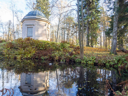 White gazebo and trees make a reflection on a little pond, sunny late autumn day in Herttoniemi park in Helsinki Finland photo