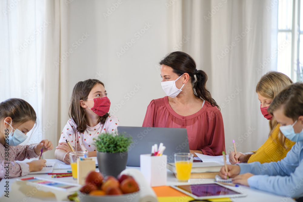 Group of homeschooling children with teacher studying indoors, coronavirus concept. Group of homeschooling children with teacher studying indoors, coronavirus concept.