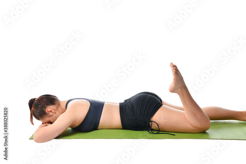 Athletic girl lies on a sports mat face down and meditates after yoga exercises.