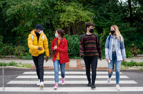 Group of young people crossing road outdoors in town, talking. Coronavirus concept. © Halfpoint