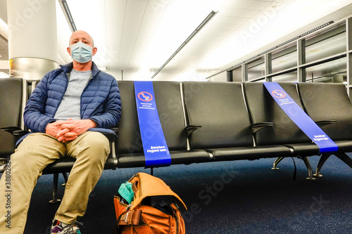 Boston Massachusetts, USA A man sits in the departure terminal at Loga aiport with social distance ribbons to prevent contact.