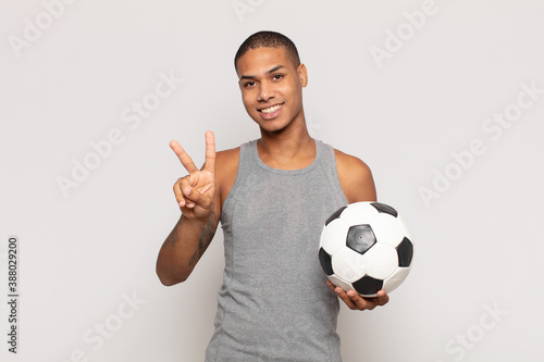 young black man smiling and looking friendly, showing number two or second with hand forward, counting down photo