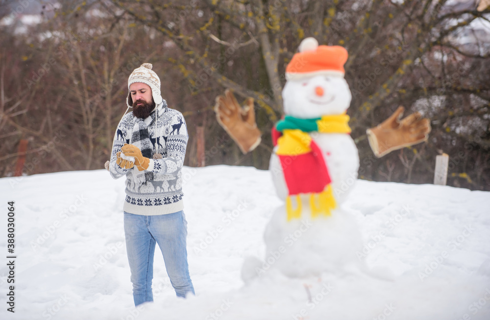 Snowman and cheerful bearded hipster knitted hat and warm gloves play with snow outdoors. Have fun winter day. Let it snow. Christmas holidays. Active lifestyle. Snow games. Leisure on fresh air