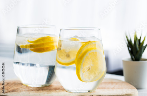 Close up two glasses of homemade detox drink, lemon and a glass of warm room temperature water. Detox drinks woman healthy lifestyle losing weight
