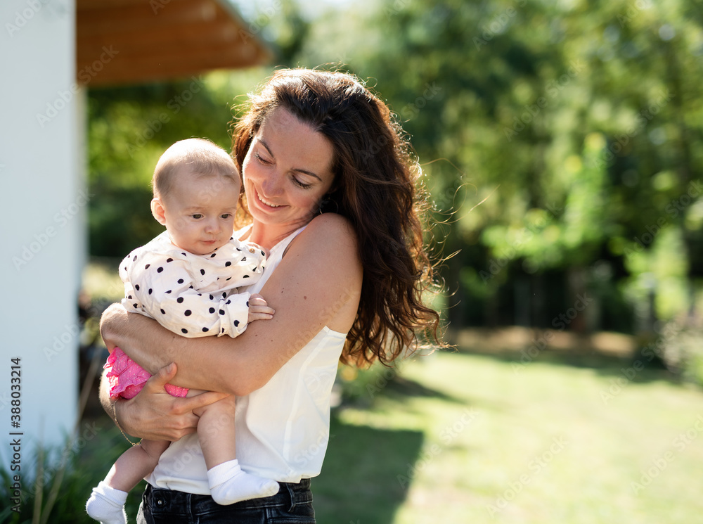 Woman holding baby daughter outdoors in backyard. Copy space. Woman holding baby daughter outdoors in backyard. Copy space.
