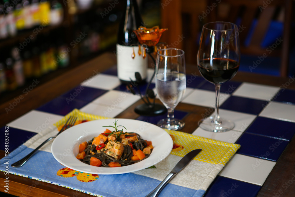 Squid ink pasta with salmon and wine in an italian restaurant