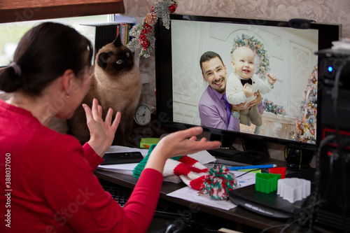 A woman is sitting at a table and talking via video link with relatives at the holiday. Staying at home, quarantine and social distancing during the New Years.