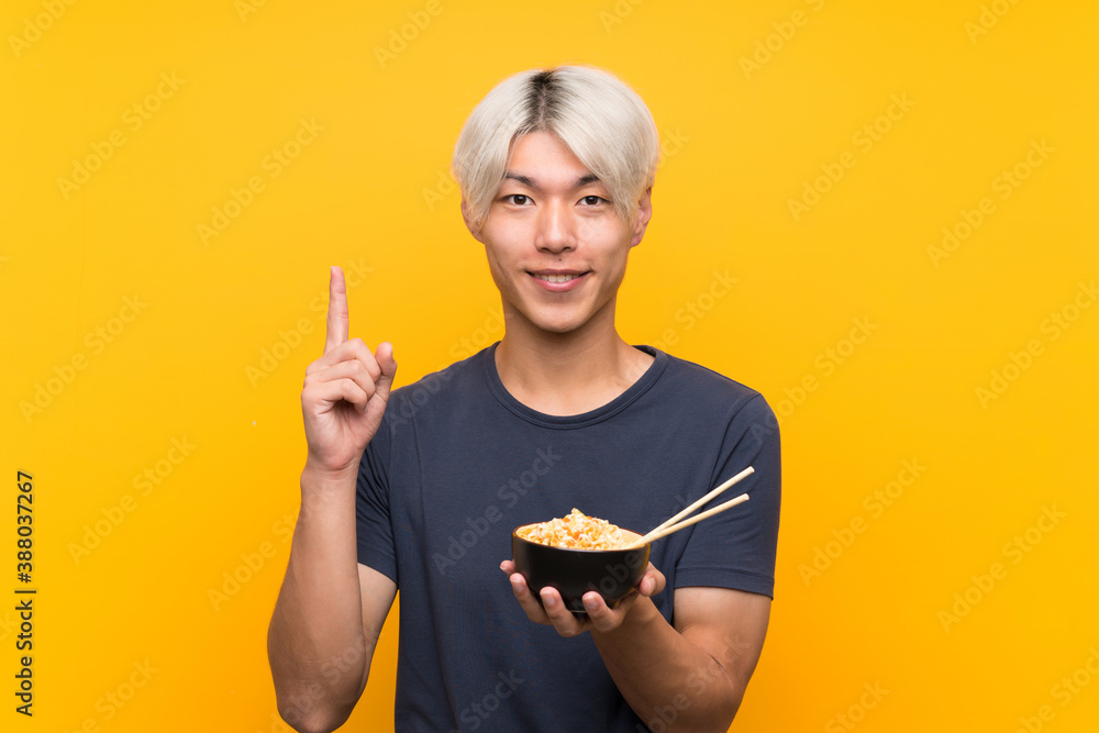 Young asian man over isolated yellow background pointing up a great idea Young asian man over isolated yellow background pointing up a great idea