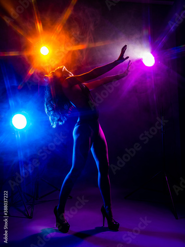 Beautiful slim sexy dancer girl wearing lingerie and high heels posing in the rays of light in a colorful smoke. Artistic, conceptual, silhouette,commercial and advertising design