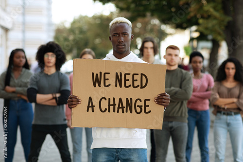 Black man with we need a change placard leading group