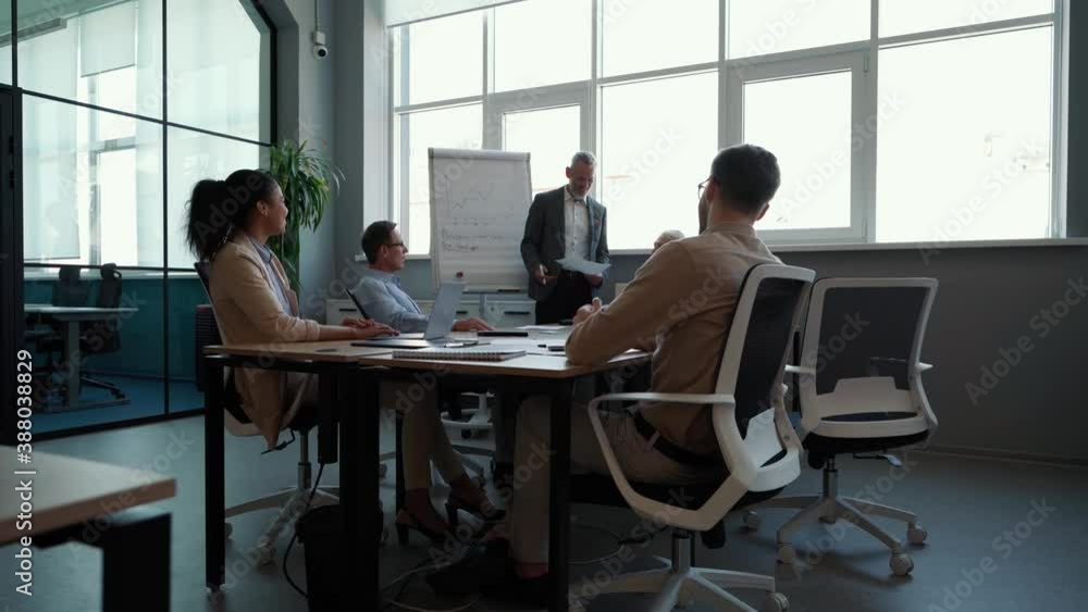 Male team leader or executive explaining business strategy on whiteboard to colleagues, giving presentation Male team leader or executive explaining business strategy on whiteboard to colleagues, giving presentation