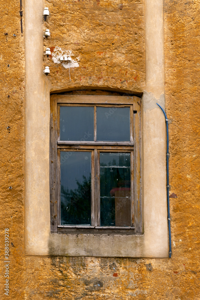 An old window in a wooden frame in the opening of an old house.