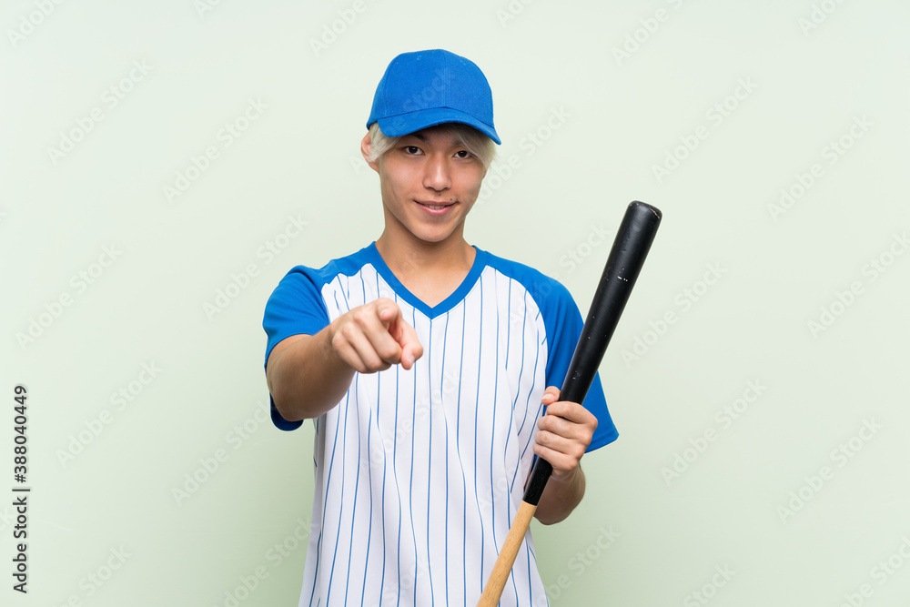 Young asian man playing baseball over isolated green background points finger at you with a confident expression Young asian man playing baseball over isolated green background points finger at you with a confident expression