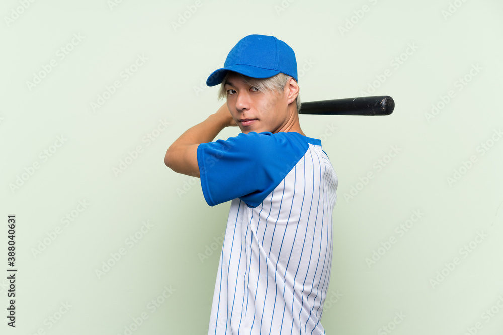 Young asian man playing baseball over isolated green background Young asian man playing baseball over isolated green background