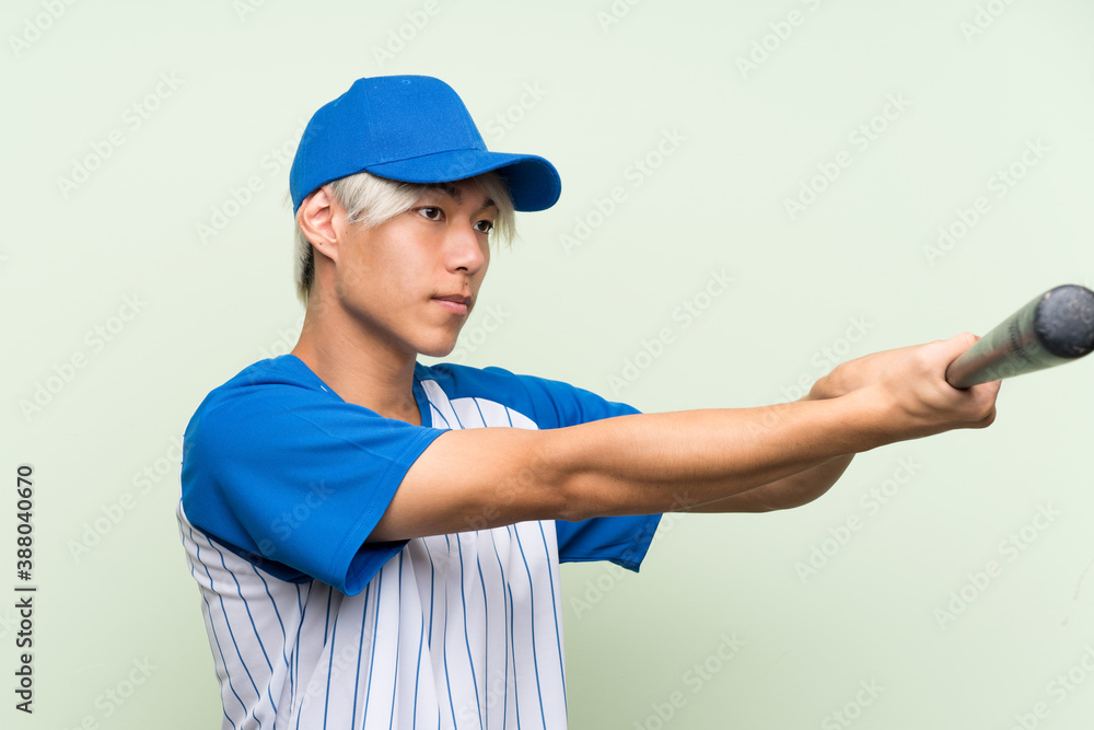 Young asian man playing baseball over isolated green background