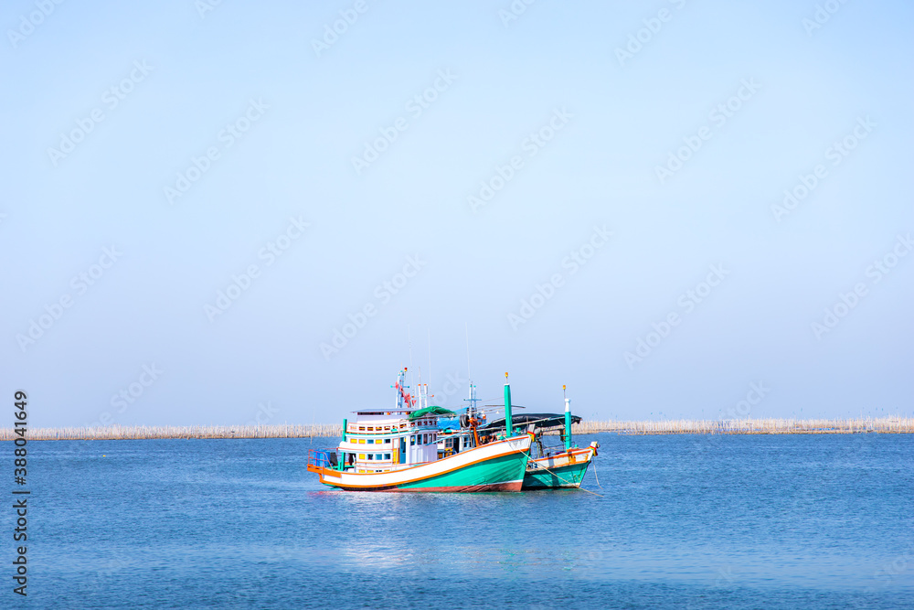 Naklejka premium Fishing boats in the sea on a clear blue sky.
