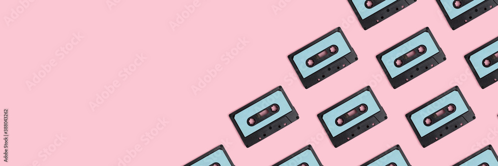 Fototapeta premium Cassette tapes pattern on a pink pastel background. Creative banner with place for text.