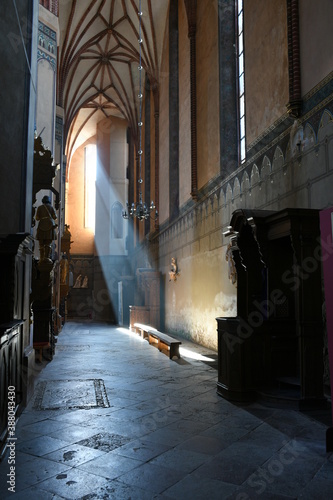 A view of an interior of an old abandoned Christian church with light rays entering it through an old wooden window frame and illuminating the floor seen on a sunny summer day on a Polish countryside