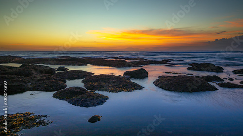 Beach during low tide. Amazing seascape. Stones covered by water. Sunset time. Golden hour. Slow shutter speed. Soft focus. Water reflection. Mengening beach, Bali, Indonesia