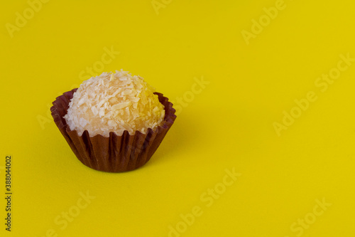 Brazilian traditional sweet isolated on yellow background. Coconut candy and condensed milk.