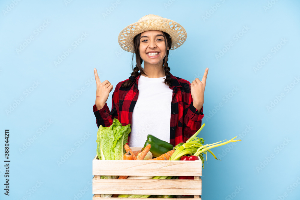 Young farmer Woman holding fresh vegetables in a wooden basket pointing up a great idea