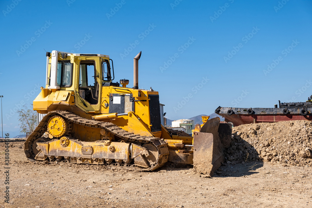 Yellow bulldozer at Drapetsona shipyard, Piraeus, Greece. Blue sky background.