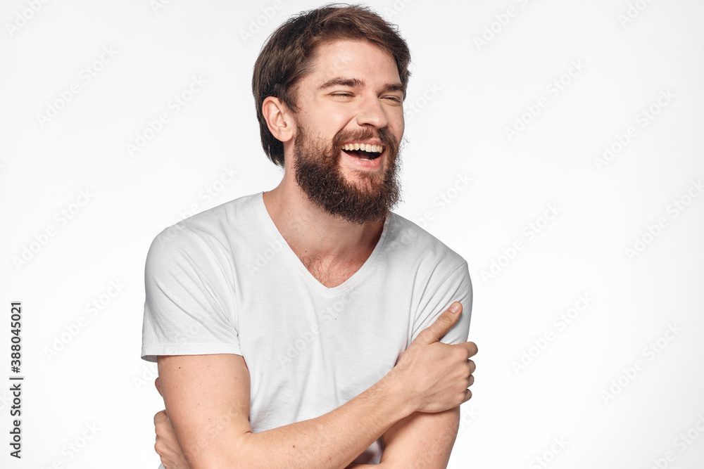 cheerful bearded man in a white t-shirt emotions gestures with his hands light background studio cheerful bearded man in a white t-shirt emotions gestures with his hands light background studio