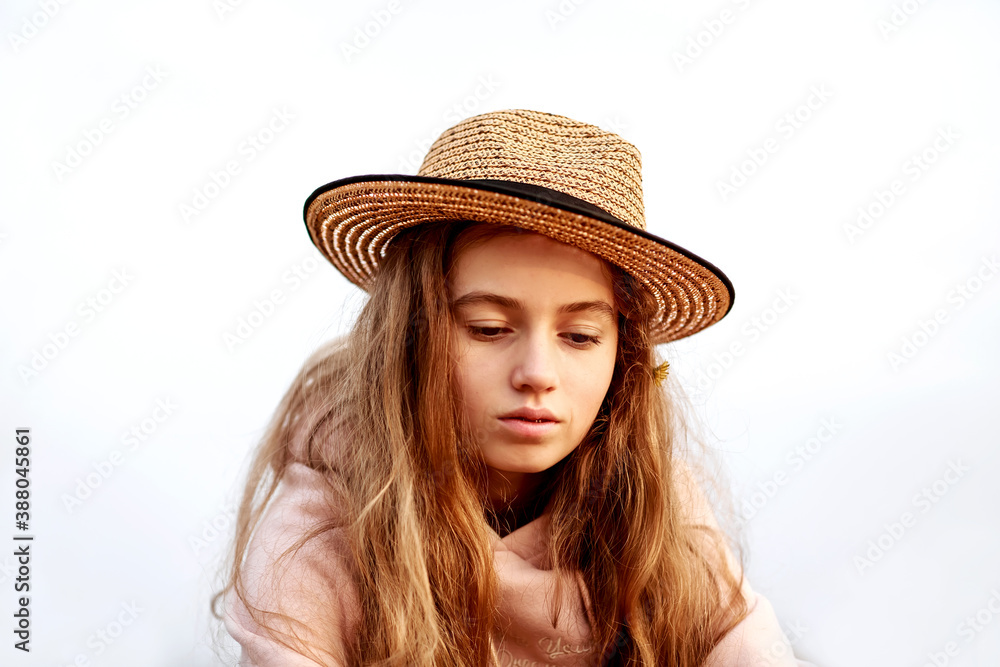 Portrait of a beautiful teenage girl in a straw hat against the sky looking down. Portrait of a beautiful teenage girl in a straw hat against the sky looking down.