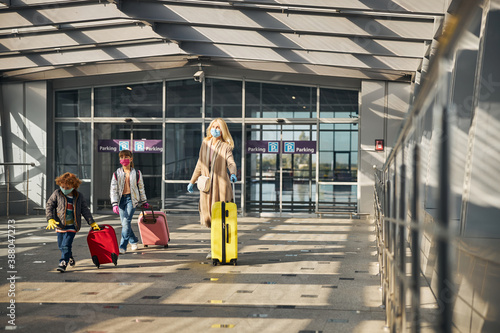 Family carrying their possessions in a sunny airport hall