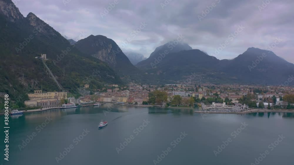 Static aerial shot of large passenger boat pulling out of the Riva Del Garda port, Italy Static aerial shot of large passenger boat pulling out of the Riva Del Garda port, Italy