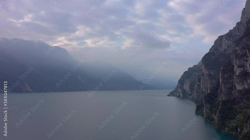 Dolly out aerial shot of lake Garda and the surrounding mountains cover in beautiful morning fog Dolly out aerial shot of lake Garda and the surrounding mountains cover in beautiful morning fog