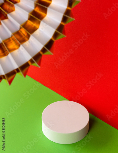White and golden paper fan on red and green creative background