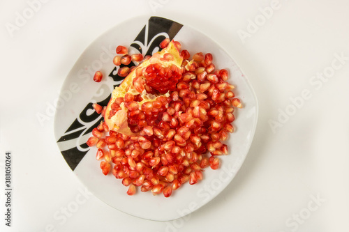 Peeled red garnet on a plate on a white background