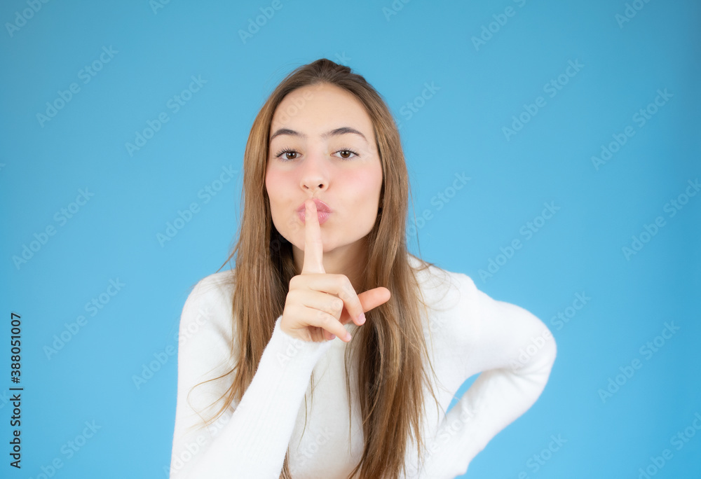 Portrait of beautiful and young woman standing over isolated blue background asking to be quiet with finger on lips. Silence and secret concept. Portrait of beautiful and young woman standing over isolated blue background asking to be quiet with finger on lips. Silence and secret concept.