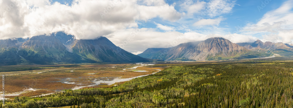 Beautiful Panoramic View of Rocky Mountains, Land and Forest on a Cloudy Summer Day in Canadian Nature. Aerial Drone Shot. Taken near Alaska Highway, Yukon, Canada.