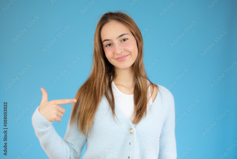 Happy positive girl pointing finger at herself, smiling at camera. Beautiful girl standing isolated over blue background. Self advertising concept Happy positive girl pointing finger at herself, smiling at camera. Beautiful girl standing isolated over blue background. Self advertising concept