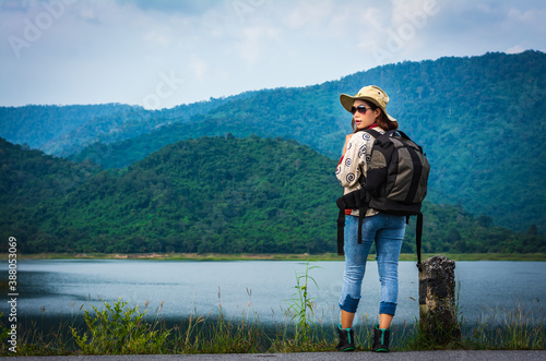 Asian woman traveler with backpack and looking at amazing mountains and forest