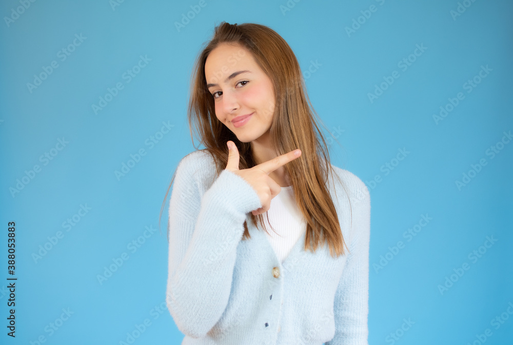Pretty girl smiling pointing finger right on blue background. Pretty girl smiling pointing finger right on blue background.