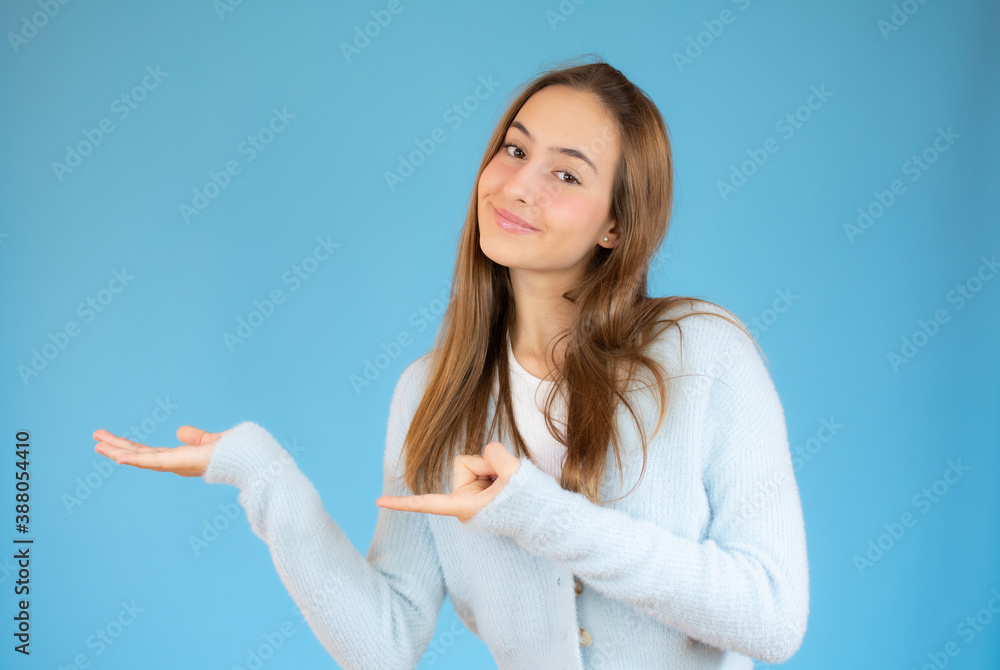 Young woman over isolated blue background holding imaginary on the palm to insert an ad Young woman over isolated blue background holding imaginary on the palm to insert an ad