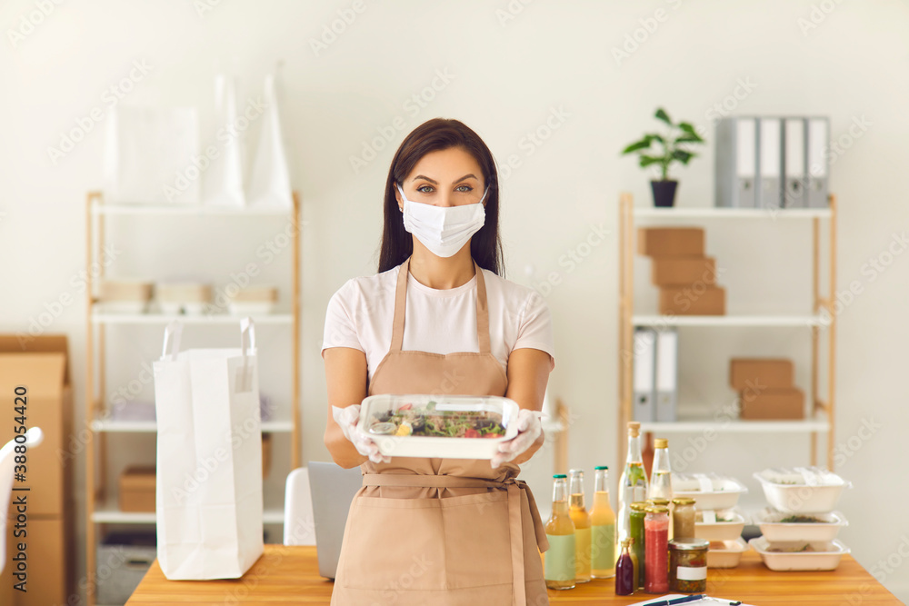 Takeaway cafe worker in face covering mask holding boxed lunch ready to be delivered to client Takeaway cafe worker in face covering mask holding boxed lunch ready to be delivered to client