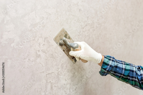 A worker makes a decorative plaster with a spatula
