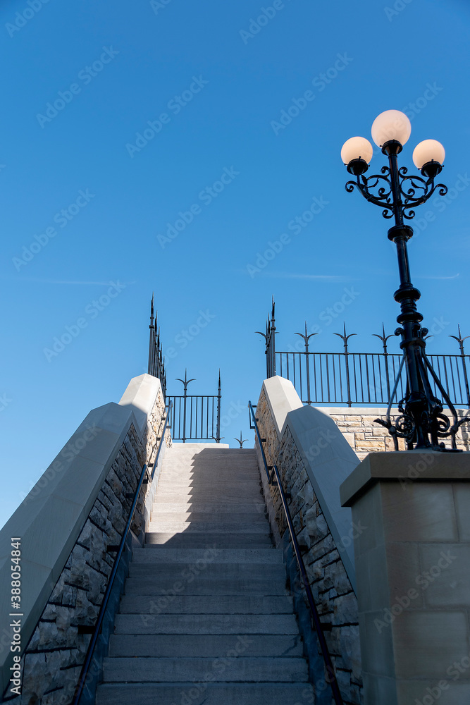 A stairway leads up to a lookout behind the Canadian Parliament building in Ottawa on a bright sunny day with a blue sky.