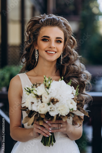 A bride in a white dress is holding a beautiful wedding bouquet.